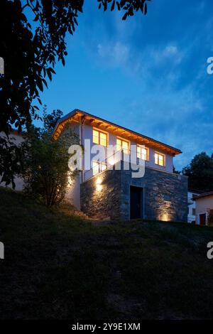 Maison individuelle juste rénovée, avec des finitions modernes. Arrière de la maison avec grand jardin verdoyant privé. Scène de nuit, personne à l'intérieur Banque D'Images