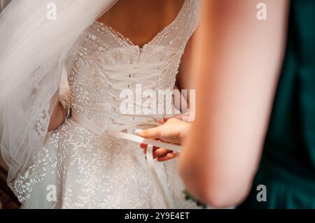 L'art délicat du laçage de robe de mariée dans un moment de mariage intime. Banque D'Images