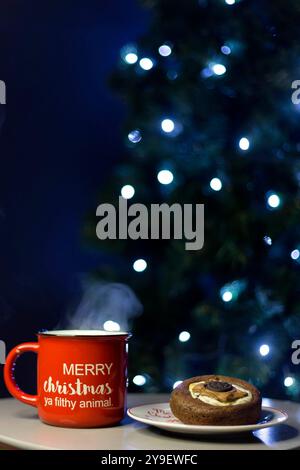 Tasse de Noël Joyeux Noël ya animal sale et cookie sur la table. Arbre de Noël bokeh. Fond de Noël Banque D'Images