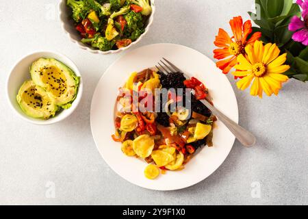 Une assiette nutritive et délicieuse avec riz noir aux légumes cuits, salade de tomates-brocolis-radis fraîches, avocat aux graines de sésame Banque D'Images