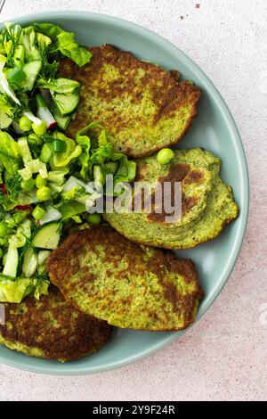 Crêpes aux courgettes et au brocoli servies avec une salade mixte de concombres, jeunes pois et radis. Ce plat végétarien sain est à la fois délicieux et nu Banque D'Images