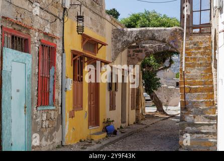 Vue pittoresque sur la rue des maisons rustiques et des escaliers en pierre peints dans des couleurs pastel dans la vieille ville de Rhodes. Banque D'Images