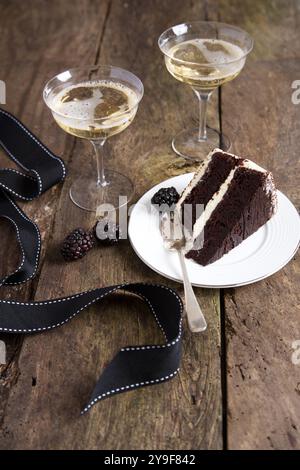 Célébrez avec style avec une riche tranche de gâteau au chocolat accompagnée d'un verre de champagne pétillant - la combinaison parfaite de plaisir et d'élégance. Banque D'Images