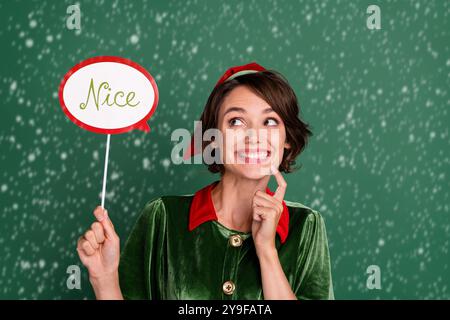 Photo de la jeune fille assez rusée tenue de tête elf tenant joli parlant bulle doigt menton isolé couleur verte fond Banque D'Images