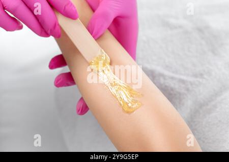 Une esthéticienne fait une épilation en pâte de sucre des bras d'une femme dans un salon de beauté. Banque D'Images