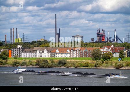 Cargo chargé de charbon, sur le Rhin près de Duisburg-Laar, maisons sur Deichstrasse, toile de fond industrielle de l'aciérie ThyssenKrupp à Bruc Banque D'Images