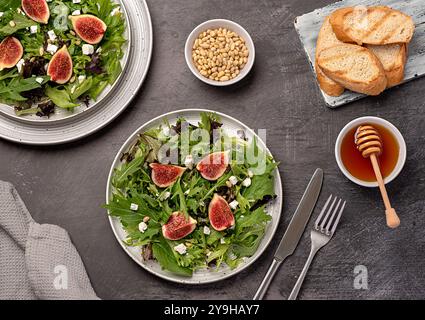 Photographie culinaire de salade à la figue et au fromage feta, épinards, laitue, miel, pignons de pin, pain grillé, table Banque D'Images