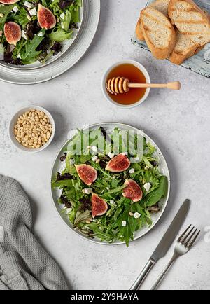 Photographie culinaire de salade à la figue et au fromage feta, épinards, laitue, miel, pignons de pin, pain grillé, table Banque D'Images