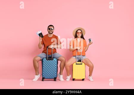 Couple heureux avec des valises, passeport, billets et appareil photo vintage sur fond rose Banque D'Images