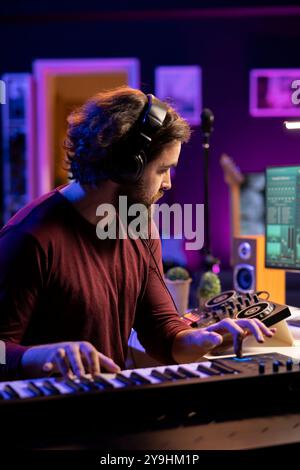 Compositeur professionnel enregistrant des notes de clavier électronique dans le home studio, jouant des sons de contrôleur midi pour appliquer des techniques de mixage et de maître. Ingénieur du son améliorant les niveaux de volume. Banque D'Images