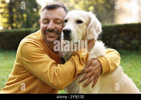 Homme souriant avec chien mignon Golden Retriever le jour du printemps Banque D'Images