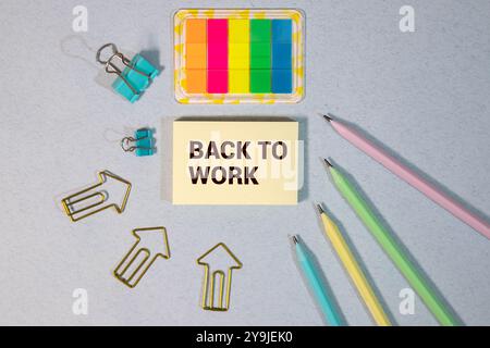 RETOUR AU TRAVAIL texte sur papier avec loupe, café et clavier sur fond gris Banque D'Images