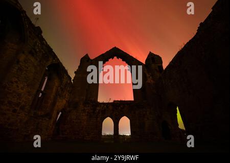 Abbaye de Haughmond, Shrewsbury. 11 octobre 2024. De vives aurores boréales brillent autour des ruines de l'abbaye de Haughmond près de Shrewsbury aux premières heures du vendredi matin. L'aurore était visible dans la plupart des régions du Royaume-Uni. Haughmond a été fondée en tant que petite chapelle ou ermitage sur une colline boisée à l'est de Shrewsbury vers 1100 et détruite. L'abbaye a été dissoute en 1539 dans le cadre de la dissolution nationale des monastères par Henri VIII. Crédit : British News and Media/Alamy Live News Banque D'Images