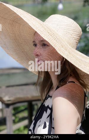 Photo de tête extérieure d'une femme portant un chapeau de paille à large bord Banque D'Images