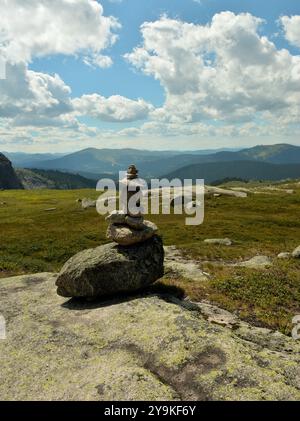 Une petite pyramide de pierre au sommet d'une grande pierre plate surplombant une vallée de montagne pittoresque sous un ciel d'été clair. Parc naturel Ergaki, Krasnoyars Banque D'Images