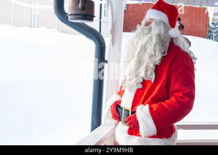 Le Père Noël est debout sur le porche et regarde le paysage enneigé Banque D'Images