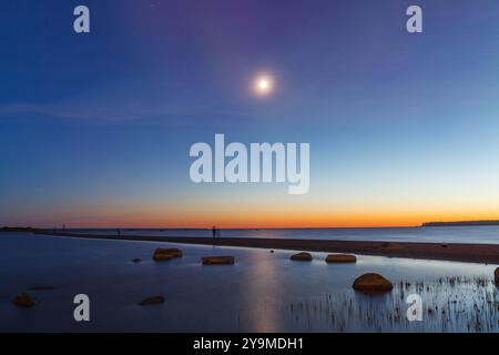 Pleine lune se levant sur la mer Baltique, vue sur le rivage de la mer, heure du coucher du soleil tardif Banque D'Images