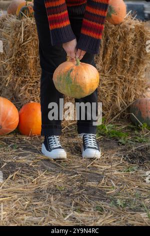 Personne tenant une grande citrouille orange par la tige Banque D'Images