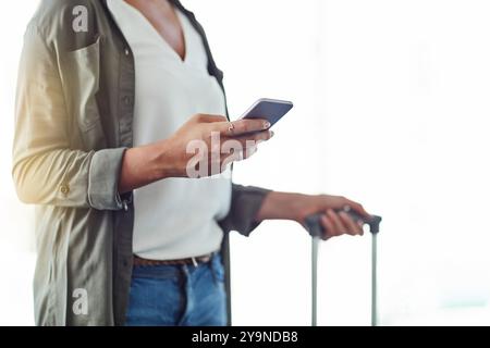 Mains, téléphone et femme avec des bagages à l'aéroport pour voyager, vérifier le temps de vol ou l'horaire pour la réservation en ligne. Voyage, bagages ou SMS touristiques pour Banque D'Images