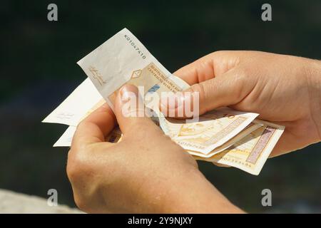 Un homme comptant de l'argent : les mains trient 10 et 100 billets convertibles bosniaques. Un voyageur avec la monnaie nationale de Bosnie-Herzégovine Banque D'Images