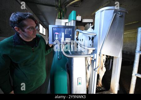 Froideville, Suisse. 10 octobre 2024. Le propriétaire de la ferme laitière David Jaccoud montre la machine à traire à Froideville, Suisse, 10 octobre 2024. Nichée au pied des Alpes et face à des pâturages luxuriants, David Jaccoud, une ferme laitière de Froideville en Suisse, abrite environ 110 vaches laitières et 200 autres animaux, produisant 2 500 litres de lait par jour. Crédit : Lian Yi/Xinhua/Alamy Live News Banque D'Images