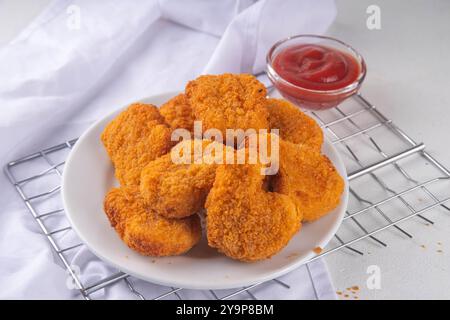 Nuggets de poulet frits dorés traditionnels sur une assiette, avec sauce ketchup. Banque D'Images