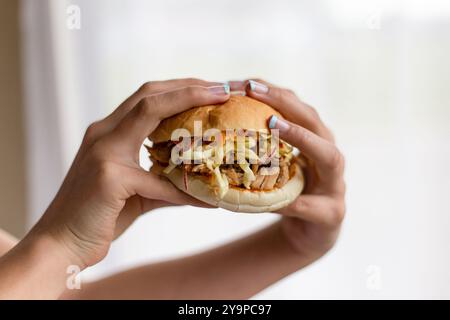 Mains ramassant un hamburger avec de la viande et de la salade Banque D'Images