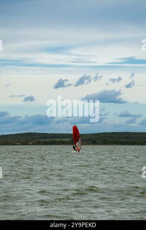 Homme planche à voile en mer contre ciel bleu. Banque D'Images