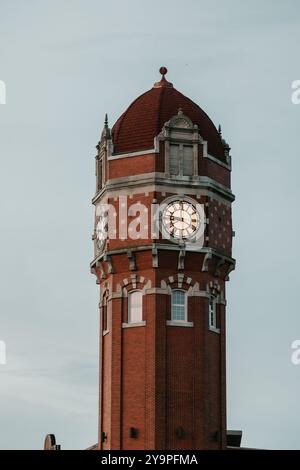 Gros plan d'une tour d'horloge en brique rouge avec un toit en dôme au crépuscule Banque D'Images