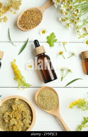 Teintures en bouteilles et différentes herbes médicinales sur table en bois blanc, pose à plat Banque D'Images