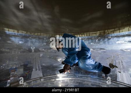 (241011) -- JIANGMEN, Oct. 11, 2024 (Xinhua) -- Un membre du personnel inspecte la sphère acrylique à l'intérieur du détecteur central de l'Observatoire souterrain de neutrinos de Jiangmen (JUNO) à Jiangmen, dans la province du Guangdong du sud de la Chine, Oct. 9, 2024. La Chine a construit le plus grand détecteur sphérique transparent du monde à 700 mètres sous terre pour capturer des neutrinos insaisissables, souvent surnommés « particules fantômes », afin de percer les secrets de l'infiniment petit et de l'infiniment vaste de l'univers. La sphère acrylique de 12 étages avec un diamètre de 35,4 mètres, enfouie profondément dans une couche de granit d'une colline à Ka Banque D'Images