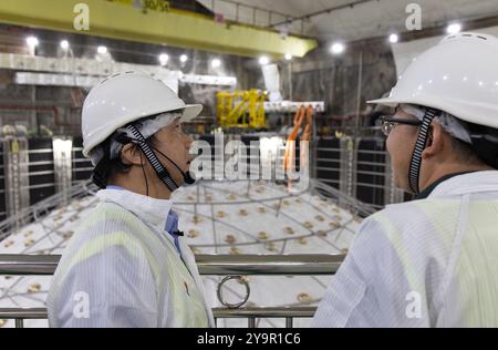 (241011) -- JIANGMEN, Oct. 11, 2024 (Xinhua) -- Wang Yifang (l), scientifique en chef de l'Observatoire souterrain de neutrinos de Jiangmen (JUNO) et chef de l'Institut de physique des hautes énergies (IHEP) du cas, s'entretient avec son collègue dans une salle d'expérimentation à Jiangmen, province du Guangdong, dans le sud de la Chine, Oct. 10, 2024. La Chine a construit le plus grand détecteur sphérique transparent du monde à 700 mètres sous terre pour capturer des neutrinos insaisissables, souvent surnommés « particules fantômes », afin de percer les secrets de l'infiniment petit et de l'infiniment vaste de l'univers. La sphère acrylique de 12 étages Banque D'Images