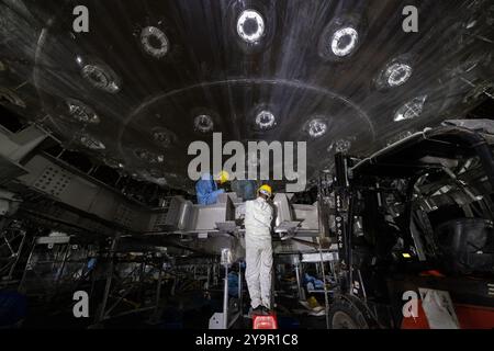 (241011) -- JIANGMEN, Oct. 11, 2024 (Xinhua) -- des membres du personnel installent la partie coquille d'un cadre en acier inoxydable du détecteur central de l'Observatoire souterrain de neutrinos de Jiangmen (JUNO) à Jiangmen, province du Guangdong, dans le sud de la Chine, Oct. 9, 2024. La Chine a construit le plus grand détecteur sphérique transparent du monde à 700 mètres sous terre pour capturer des neutrinos insaisissables, souvent surnommés « particules fantômes », afin de percer les secrets de l'infiniment petit et de l'infiniment vaste de l'univers. La sphère acrylique de 12 étages avec un diamètre de 35,4 mètres, enfouie profondément dans une laye de granit Banque D'Images