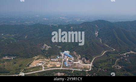 (241011) -- JIANGMEN, 11 octobre 2024 (Xinhua) -- une photo de drone aérien montre les installations au sol de l'Observatoire souterrain de neutrinos de Jiangmen (JUNO) à Jiangmen, dans la province du Guangdong du sud de la Chine, 10 octobre 2024. La Chine a construit le plus grand détecteur sphérique transparent du monde à 700 mètres sous terre pour capturer des neutrinos insaisissables, souvent surnommés « particules fantômes », afin de percer les secrets de l'infiniment petit et de l'infiniment vaste de l'univers. La sphère acrylique de 12 étages avec un diamètre de 35,4 mètres, enfouie profondément dans une couche de granit d'une colline à Kaiping, Jiangmen City in Banque D'Images