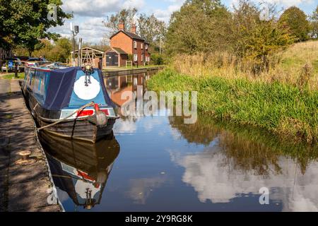 Homme marchant à dos le long du chemin de halage du canal de Caldon dans le Staffordshire approchant des services de Park Lane avec des bateaux étroits amarrés Banque D'Images