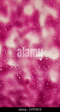 Liquide magenta formant des formes abstraites avec des bulles. Photo mobile verticale Banque D'Images