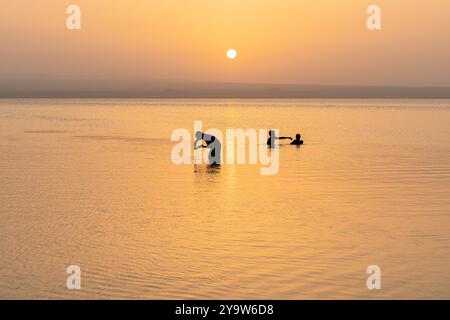 Travailleurs de l'industrie des mines de sel lavant et nageant dans le lac afrera au coucher du soleil, dépression de Danakil, région d'Afar, Ethiopie Banque D'Images