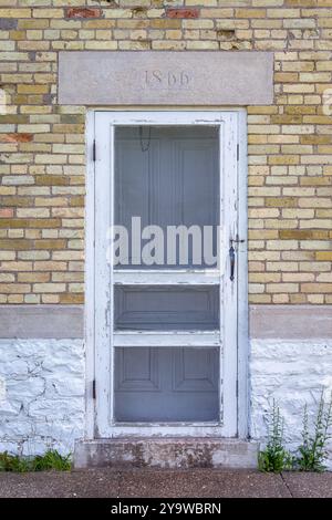 Porte blanche dans un bâtiment en briques jaunes qui date de 1866 comme indiqué par l'en-tête en pierre. Entrée au phare historique de Copper Harbor sur le lac Sup Banque D'Images
