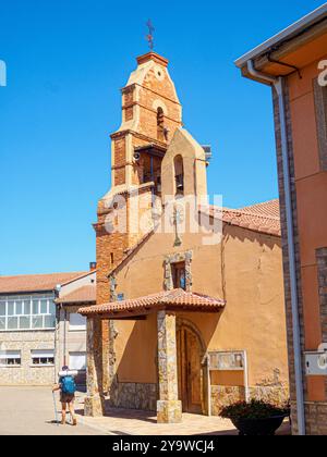 Un pèlerin avec des bâtons de randonnée marche vers l'église Iglesia de Virgen de las Candelas à Villavante, un arrêt clé sur le Camino de Santiago. Espagne. Banque D'Images