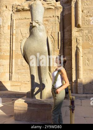 Edfou, Egypte ; 17 janvier 2024 : touriste sentant la puissance des dieux tout en contemplant le regard faucon d'Horus. Exploration du Temple d'Edfou Banque D'Images