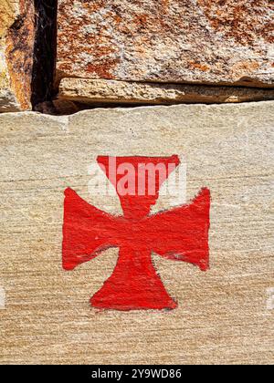 Une croix rouge des Templiers, associée aux Templiers, peinte sur un mur de pierre brute. Espagne. Banque D'Images