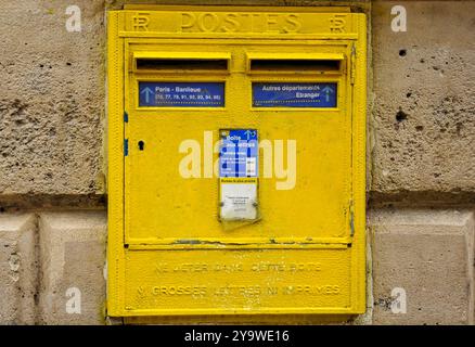 Charme français : l'emblématique boîte aux lettres jaune dans un trottoir de Paris Banque D'Images