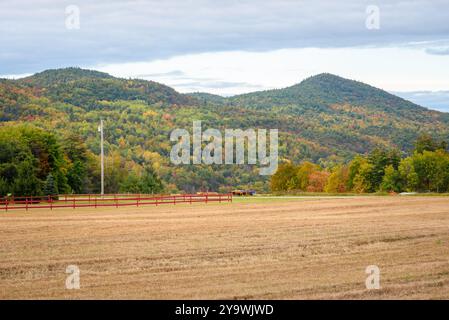 Champ récolté avec des montagnes boisées en abcès un jour d'automne partiellement nuageux Banque D'Images