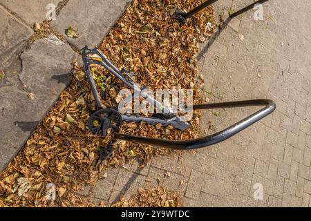 Cadre de vélo gris abandonné encore attaché à un support de vélo et couché en automne congé dans le centre-ville de York. Banque D'Images