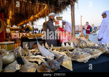 Doha, Qatar - 29 novembre 2023 : un homme arabe répare un filet de pêche pendant le festival des roulements à voile dans le village de Katara. Banque D'Images