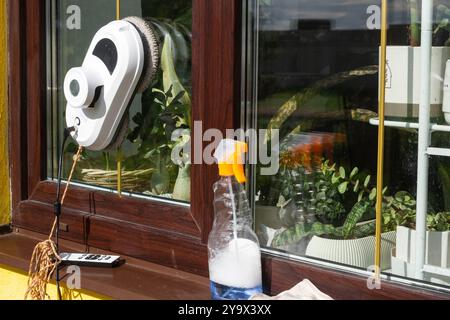 Un robot nettoyeur de vitres nettoie les fenêtres d'une maison de l'extérieur. Assistant de nettoyage, nettoyage sûr des vitres, télécommande Banque D'Images