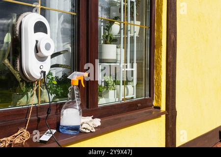 Un robot nettoyeur de vitres nettoie les fenêtres d'une maison de l'extérieur. Assistant de nettoyage, nettoyage sûr des vitres, télécommande Banque D'Images