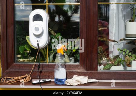 Un robot nettoyeur de vitres nettoie les fenêtres d'une maison de l'extérieur. Assistant de nettoyage, nettoyage sûr des vitres, télécommande Banque D'Images