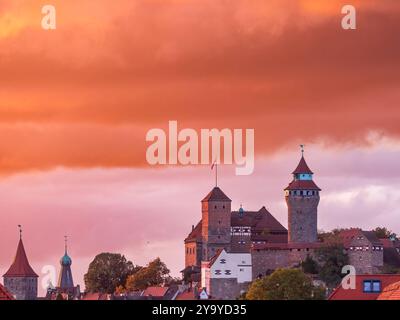 Kaiserburg Nürnberg im Sonnenuntergang, 11.10.2024 Die Kaiserburg in Nürnberg erstrahlt im intensiven Licht eines herstlichen Sonnenuntergangs. Die massiven Türme und das Dach der Burg sind vor einem dramatisch gefärbten, orange-roten Himmel zu sehen. IM Vordergrund befinden sich die Dächer der Stadt, während die Burg sich eindrucksvoll gegen den Abendhimmel abhebt. Nuernberg Wöhrd Bayern Deutschland *** Château impérial de Nuremberg au coucher du soleil, 11 10 2024 le Château impérial de Nuremberg brille dans la lumière intense d'un coucher de soleil d'automne contre les tours massives et le toit du château peuvent être vus Banque D'Images