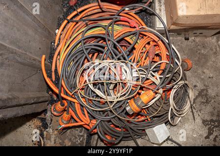 Photographie de câbles électriques usagés et sales qui ont été laissés sans surveillance et jetés sur un sol sale dans une usine. Banque D'Images